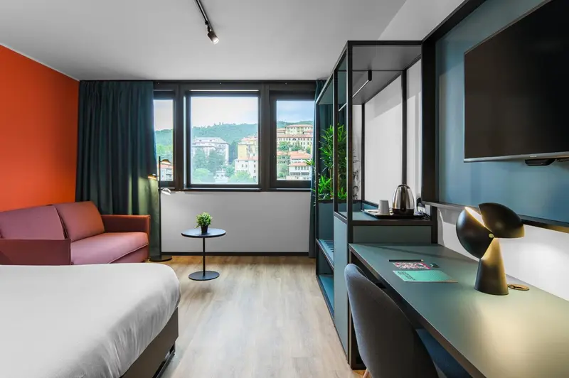 Une chambre lumineuse avec un canapé rouge et un bureau près de la fenêtre.