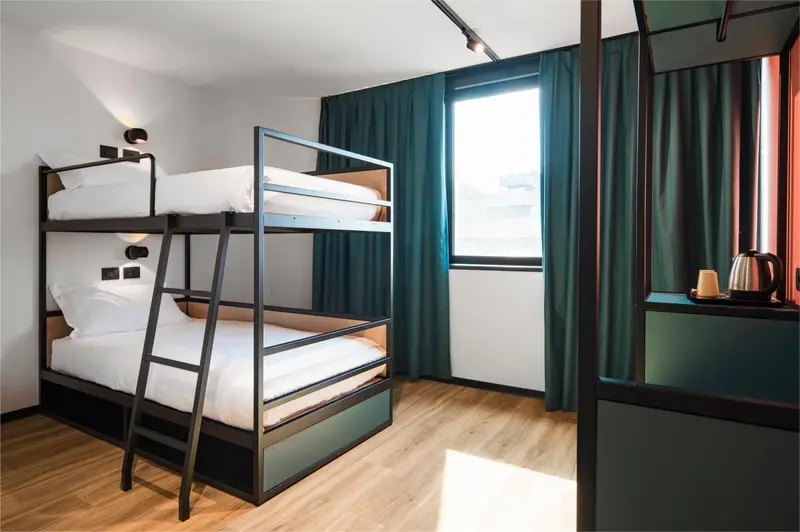 Une chambre avec un lit superposé et une fenêtre.