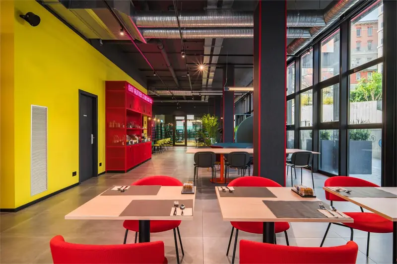 Une salle lumineuse avec des tables et des chaises rouges et noires.