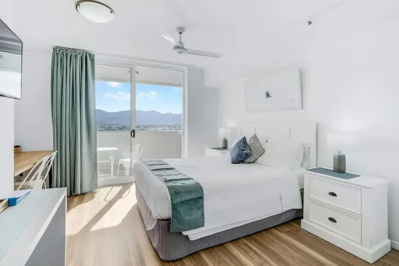 Chambre lumineuse avec un grand lit et une vue sur les montagnes.