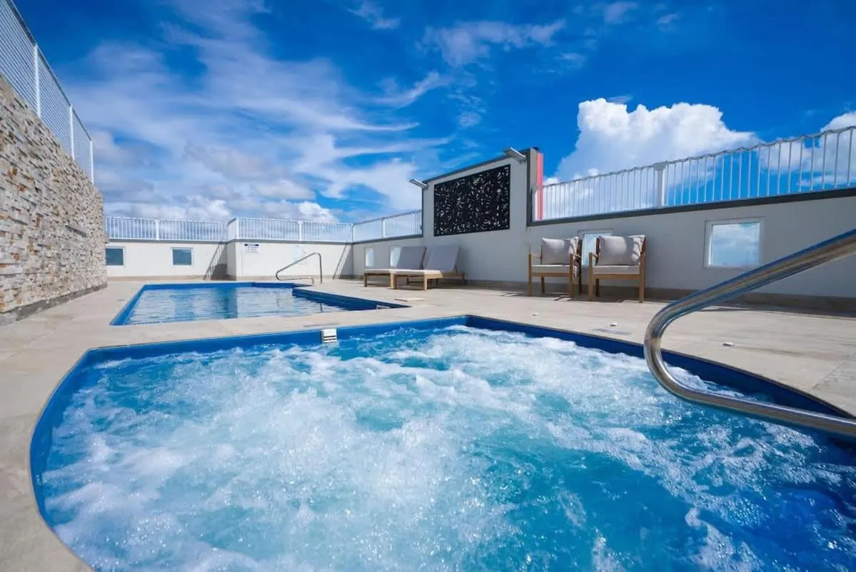 Une piscine avec un jacuzzi intégré sur un toit-terrasse ensoleillé.