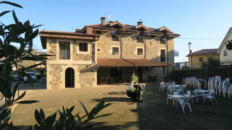 Bâtiment en pierre avec terrasse pavée et mobilier de jardin.