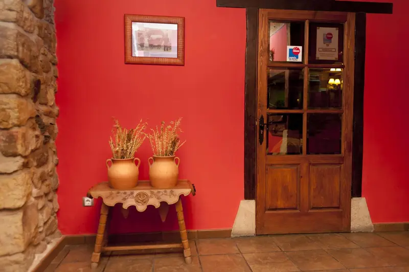 Une porte en bois sombre s'ouvre sur un espace intérieur éclairé.