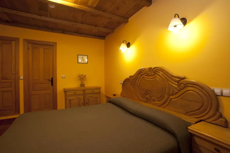 Une chambre à coucher avec un grand lit sculpté et des murs jaunes.