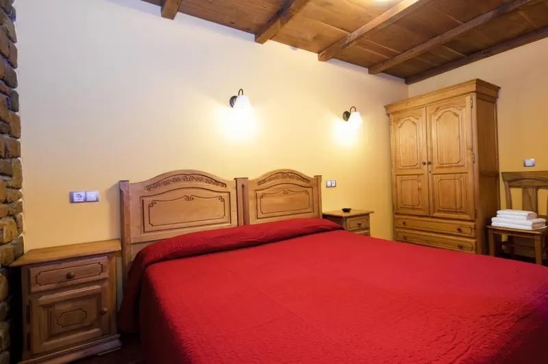 Une chambre à coucher avec un grand lit recouvert d'une couverture rouge et un meuble en bois.