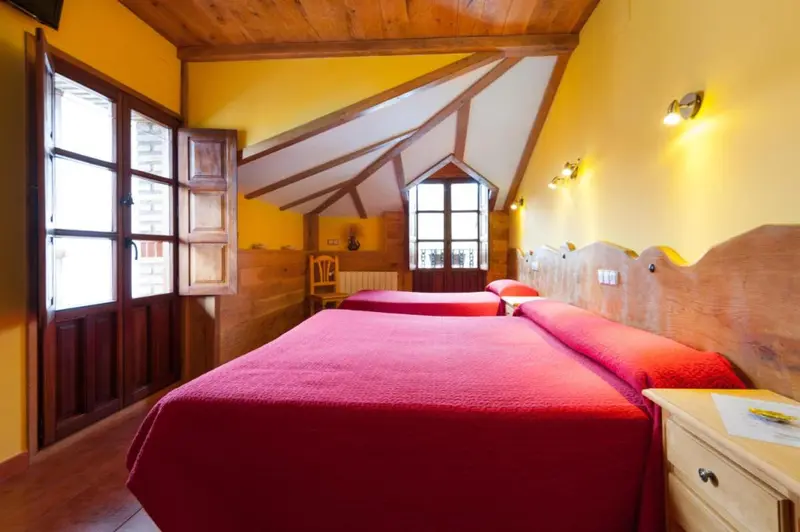 Chambre aux murs jaunes et au plafond en bois avec deux lits simples.