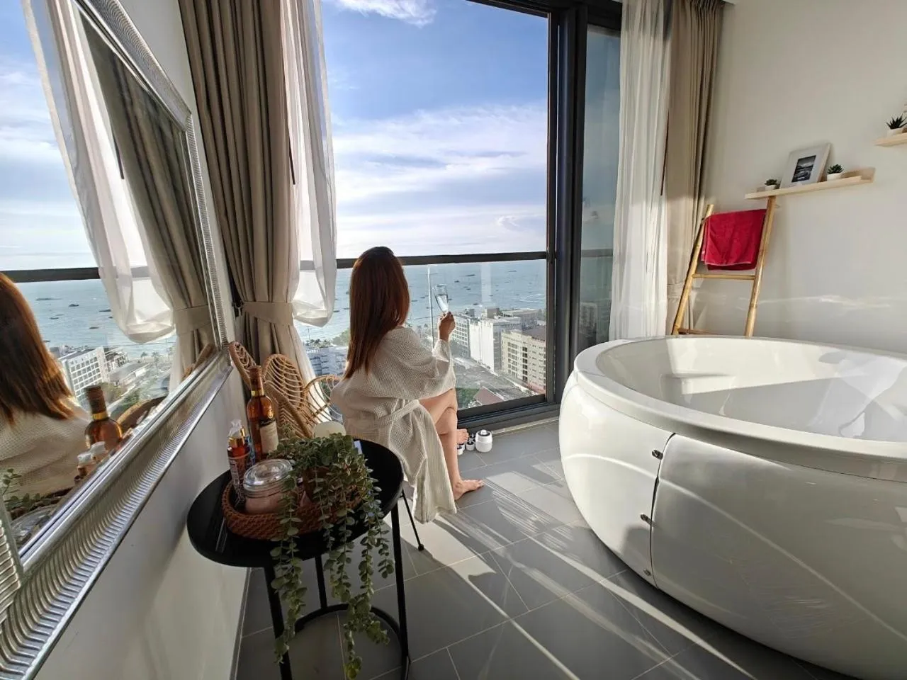 Une personne est assise sur un balcon avec vue sur la mer et la ville.