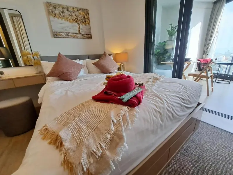 Une chambre lumineuse avec un grand lit recouvert d'une couverture et de coussins.