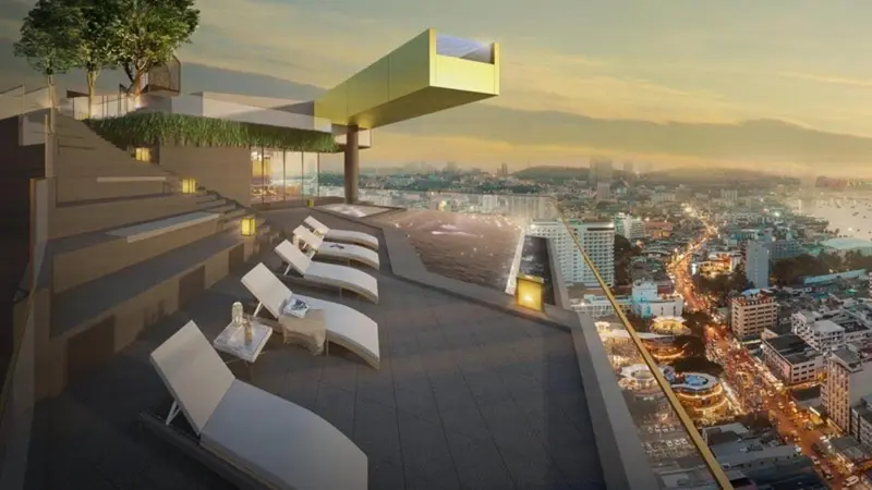 Terrasse avec transats et vue sur la ville au coucher du soleil.