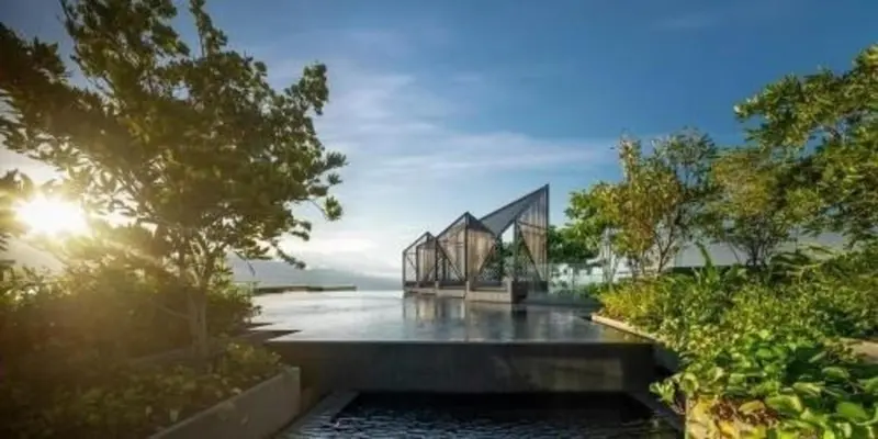 Une piscine à débordement avec des structures architecturales modernes et une végétation luxuriante.