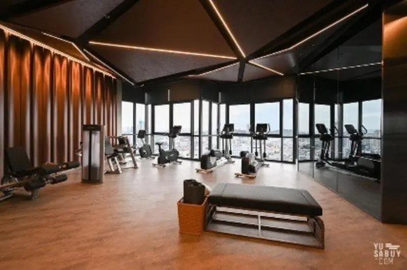 Une salle de sport lumineuse avec des équipements de fitness et une grande baie vitrée.