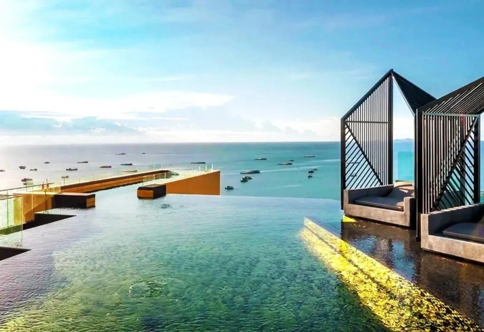 Piscine à débordement avec vue sur la mer et des bateaux à l'horizon.