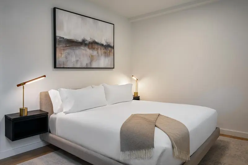 Une chambre lumineuse avec un grand lit et des lampes de chevet.