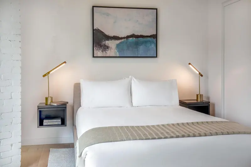 Une chambre lumineuse avec un grand lit recouvert de draps blancs et d'une couverture.