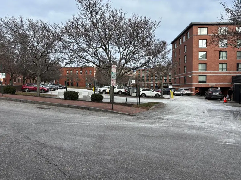 Parking devant un bâtiment en briques et des arbres dégarnis.