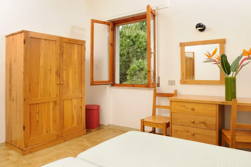 Une chambre lumineuse avec un meuble de rangement et une coiffeuse en bois.