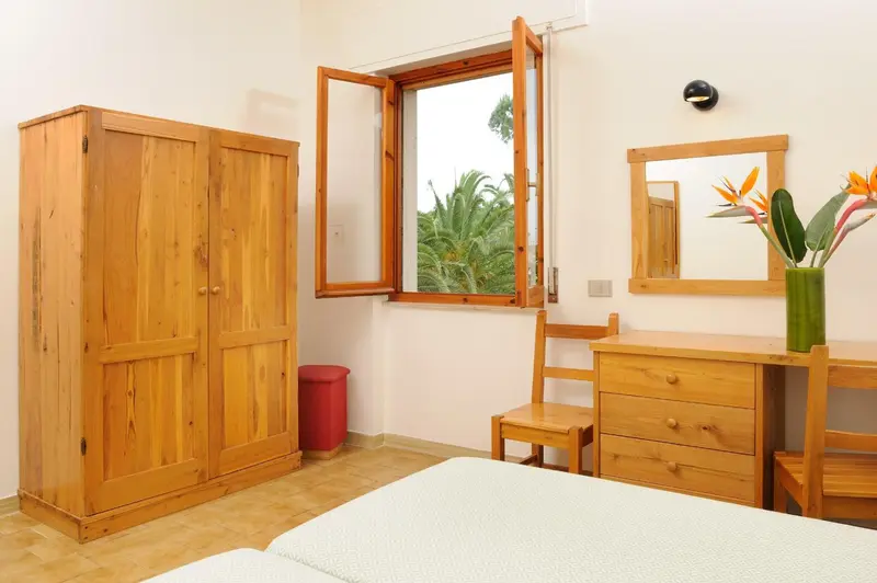 Une chambre lumineuse avec un bureau en bois et une armoire.
