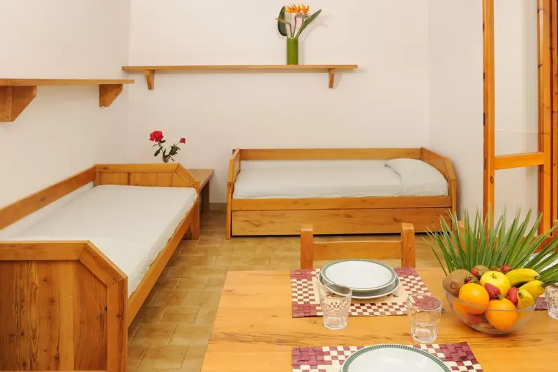 Intérieur clair avec des banquettes en bois et une table garnie de fruits.
