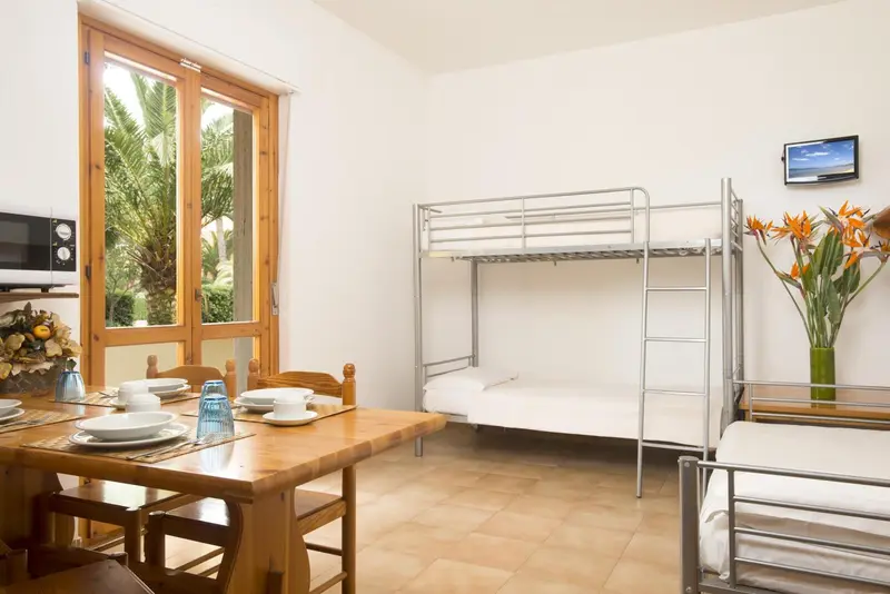Une table est dressée devant une fenêtre ouverte sur un jardin tropical.