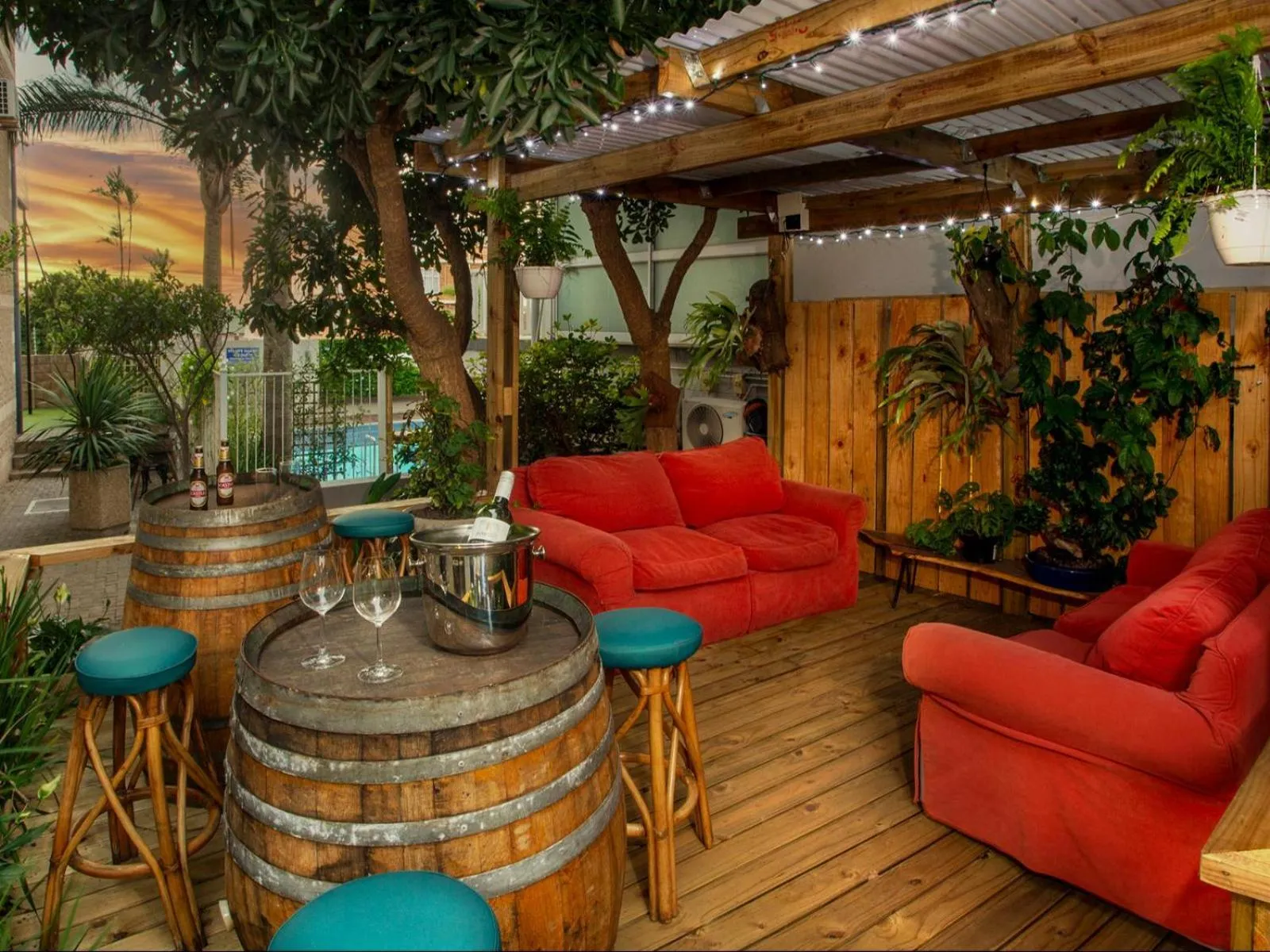Espace de détente extérieur avec mobilier en bois et canapés colorés.