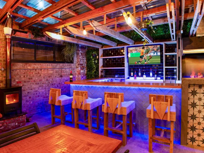 Un bar lumineux avec des tabourets en bois et un éclairage bleu.