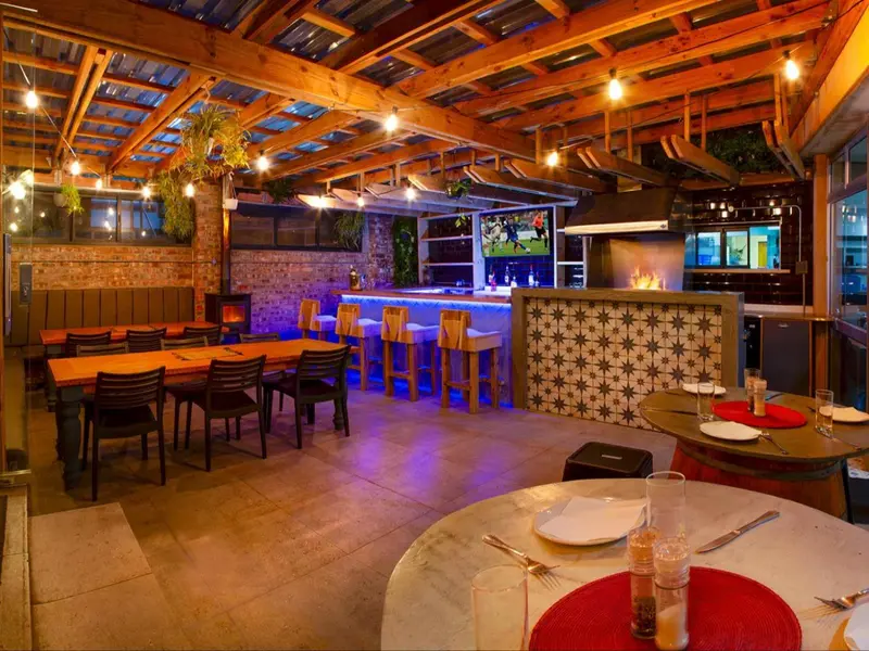 Une salle de restaurant lumineuse avec des tables et un bar éclairé.