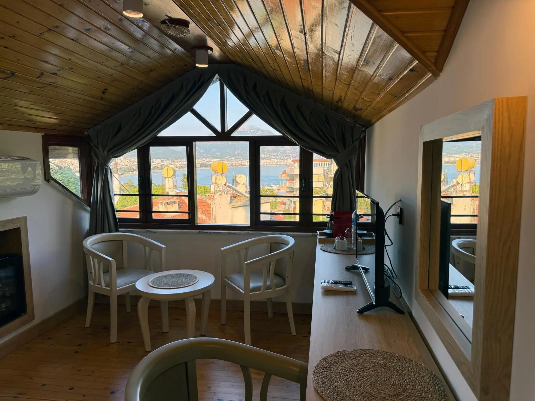Une pièce lumineuse avec deux fauteuils et une table basse face à une vue sur la mer et la ville.