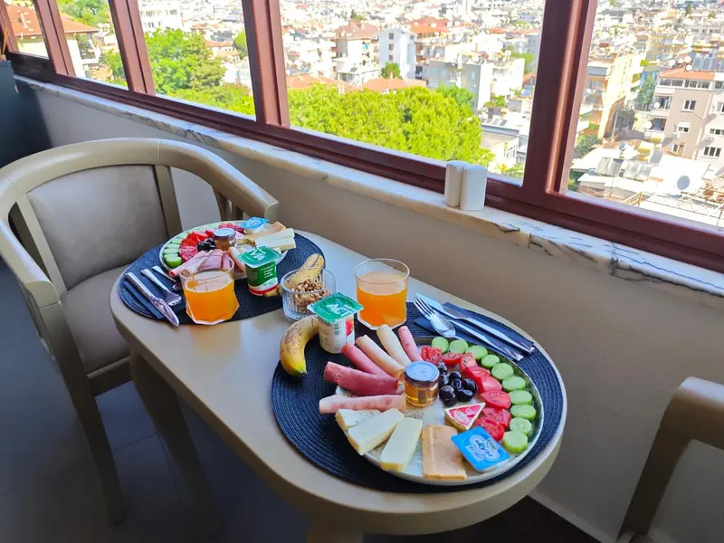 Une table de petit-déjeuner est dressée sur un balcon avec vue sur la ville.