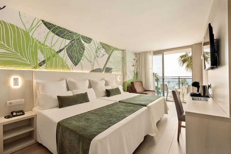 Chambre lumineuse avec lits jumeaux et vue sur la mer.