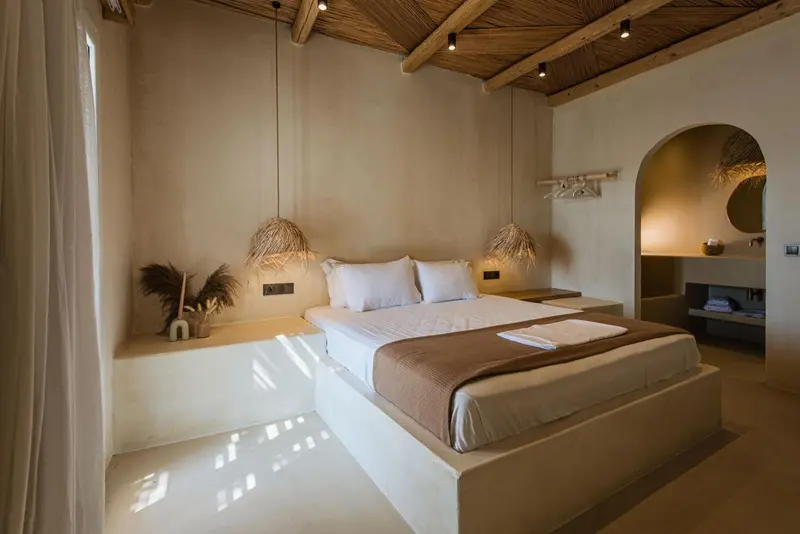 Une chambre lumineuse avec un grand lit et une décoration naturelle.