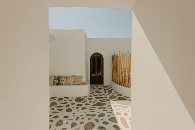 Espace intérieur lumineux avec sol en galets et assise murale.
