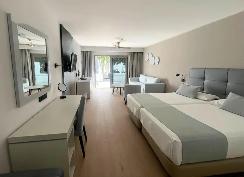 Une chambre lumineuse avec un grand lit et un espace salon.
