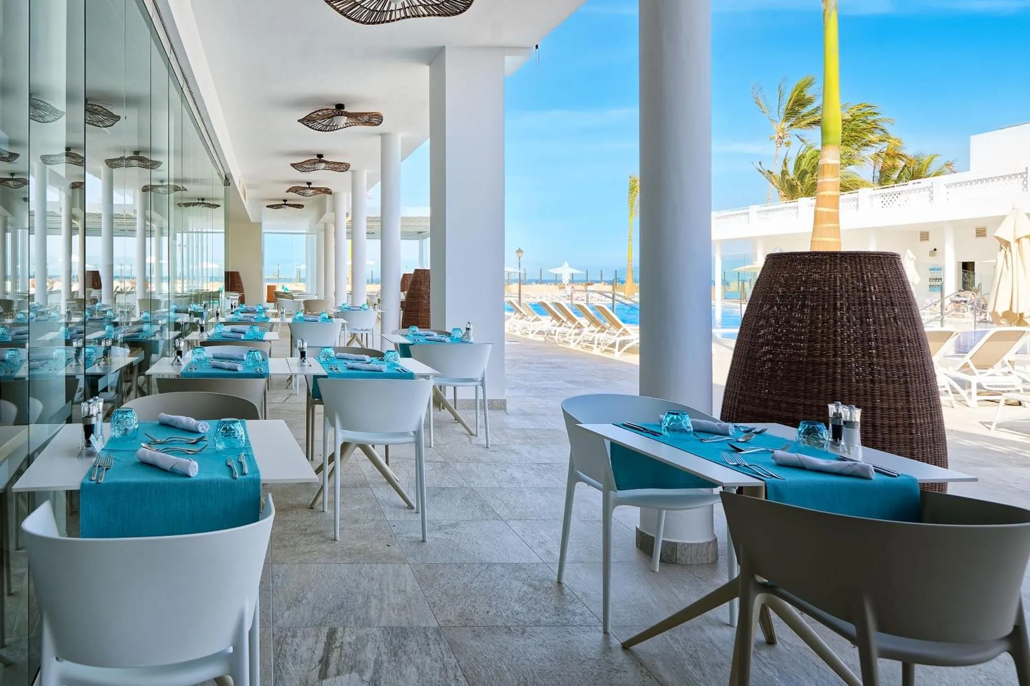 Une salle à manger lumineuse avec des tables dressées et une vue sur la mer.