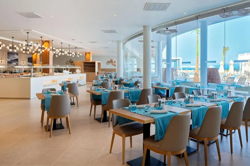 Une salle lumineuse avec des tables dressées pour un repas.