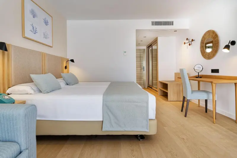 Une chambre lumineuse avec un grand lit et un bureau en bois.