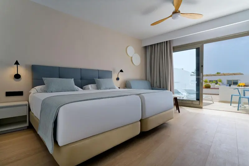 Une chambre lumineuse avec un grand lit et un accès à une terrasse.