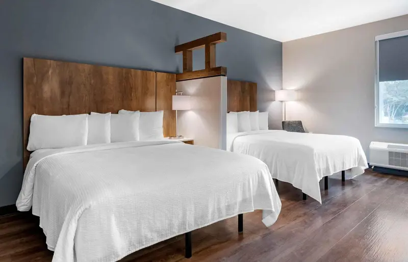 Une chambre d'hôtel avec deux lits doubles et une décoration sobre.