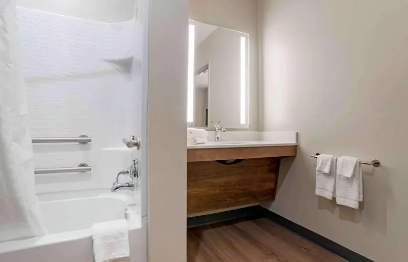 Salle de bain moderne avec baignoire et lavabo lumineux.