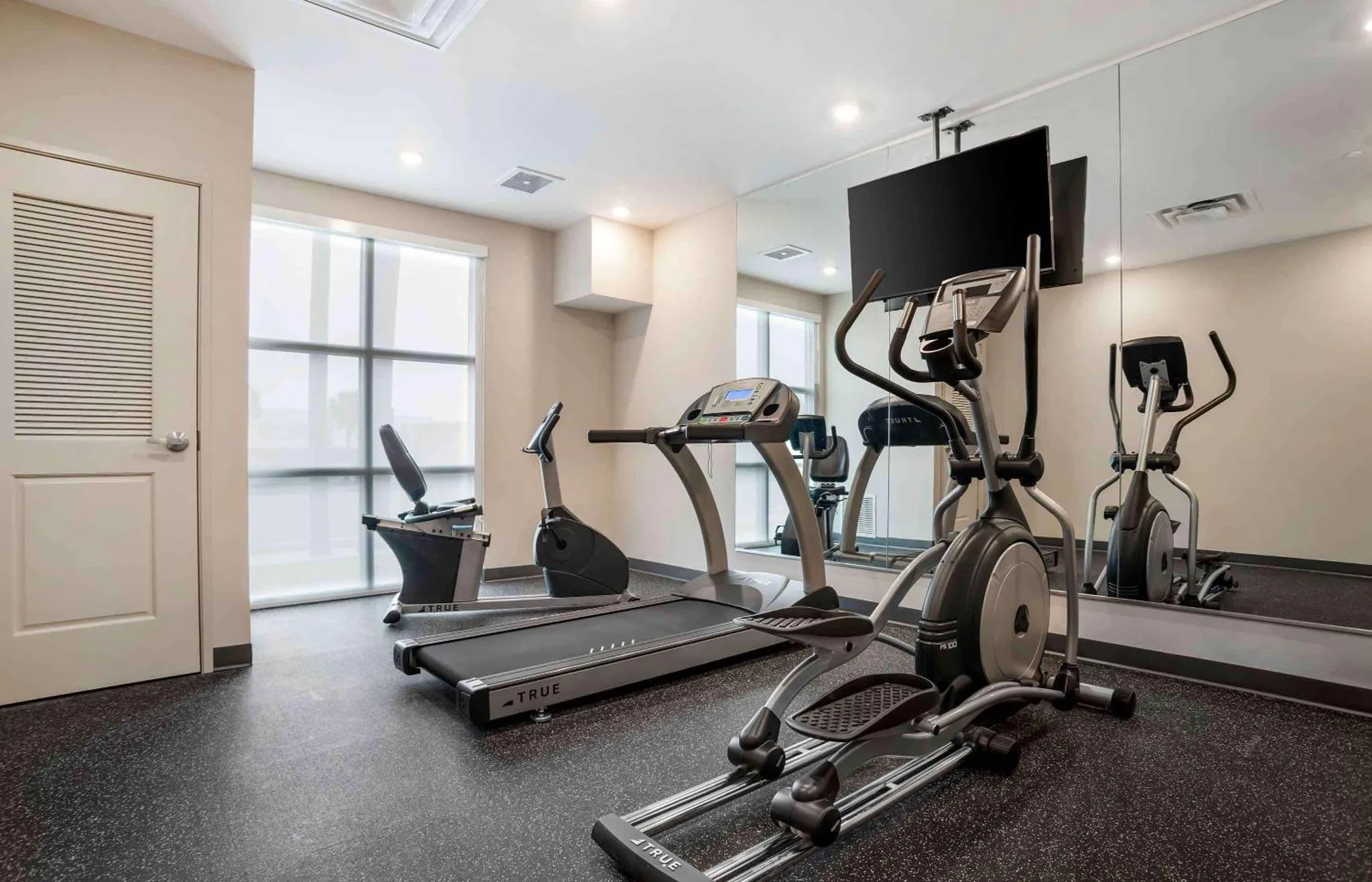 Une salle de sport lumineuse avec plusieurs appareils de fitness.