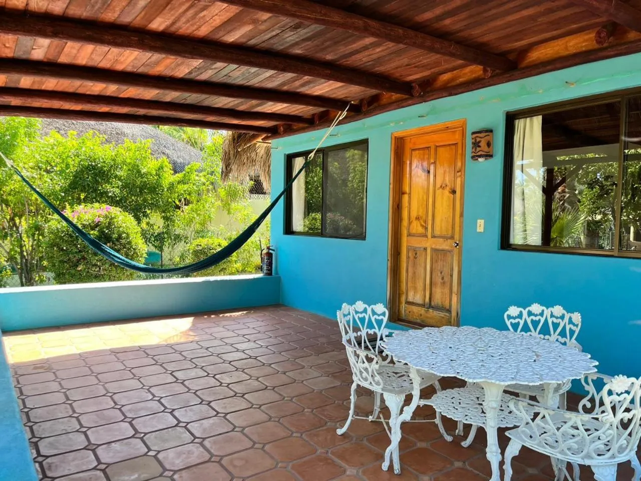 Terrasse ombragée avec mobilier en fer forgé et hamac.
