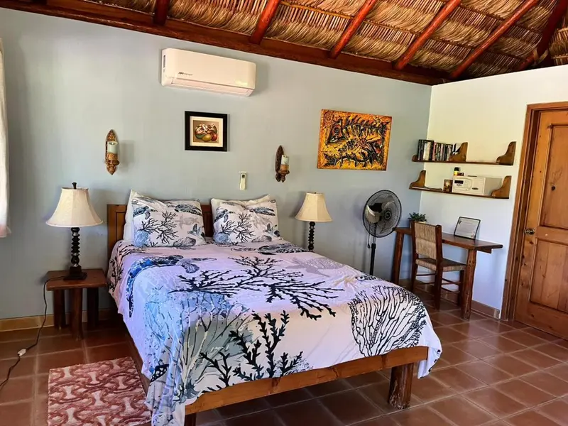 Une chambre lumineuse avec un lit recouvert d'une courtepointe marine et des tableaux décoratifs.