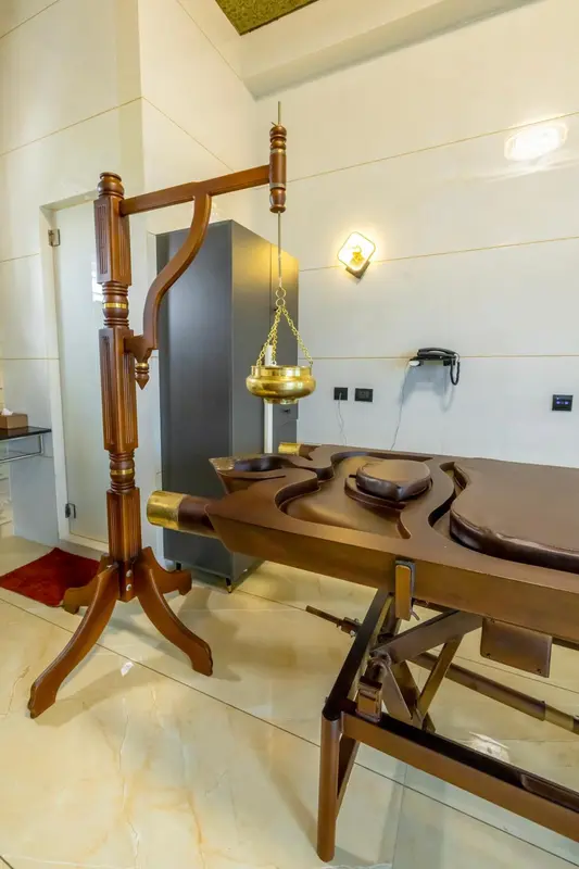 Une table de massage en bois est présente dans une pièce lumineuse.