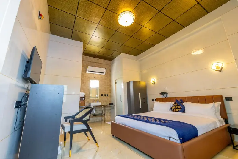 Une chambre lumineuse avec un grand lit et un téléviseur mural.