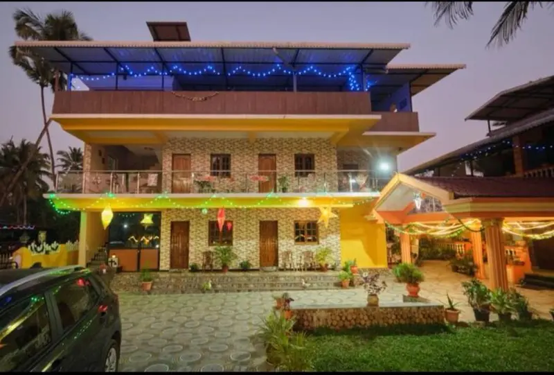 Bâtiment jaune à deux étages avec des balcons et une végétation luxuriante devant.