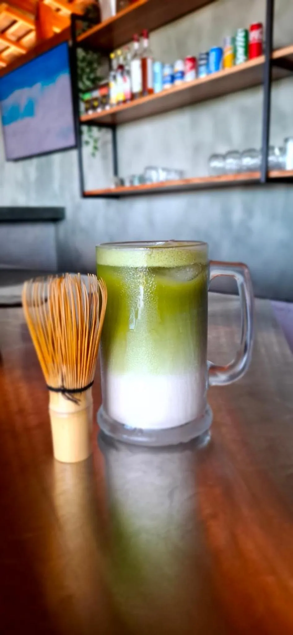 Un verre de boisson verte est posé sur une table en bois.