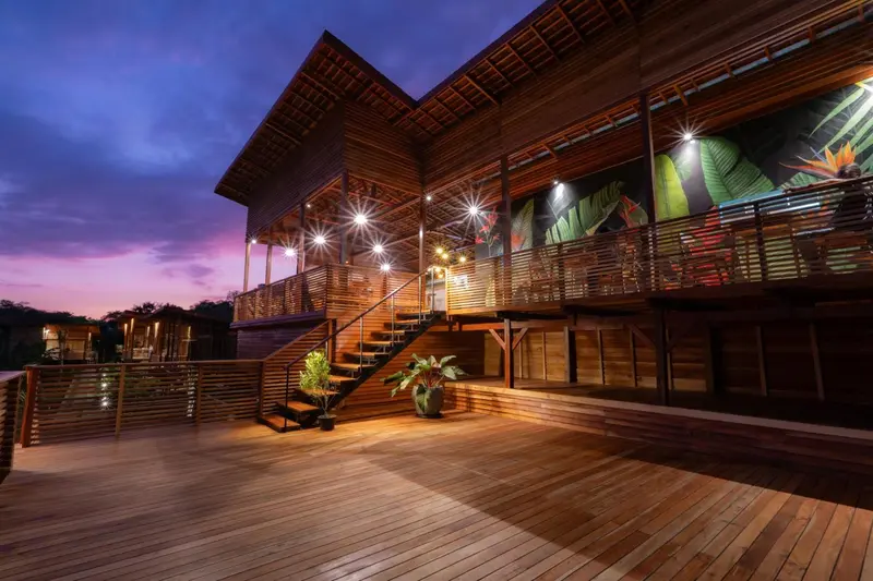Terrasse en bois éclairée d'un bâtiment moderne en soirée.