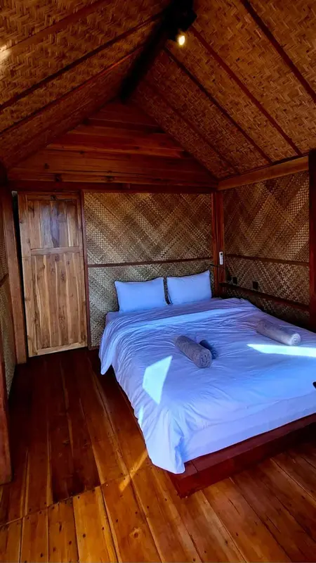Une chambre lumineuse avec un lit recouvert de blanc et des murs en bois tressé.
