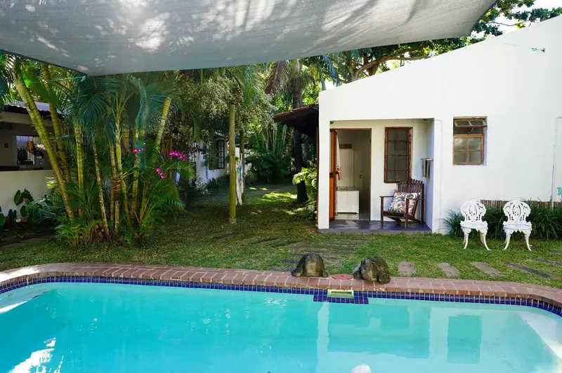Une piscine turquoise bordée d'une pelouse verdoyante et de végétation tropicale.