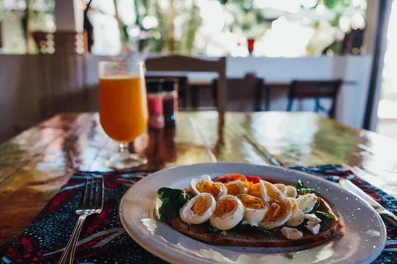 Une assiette de pain tartiné et un verre de jus d'orange sont posés sur une table.
