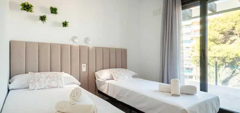Une chambre lumineuse avec deux lits simples et une vue sur l'extérieur.
